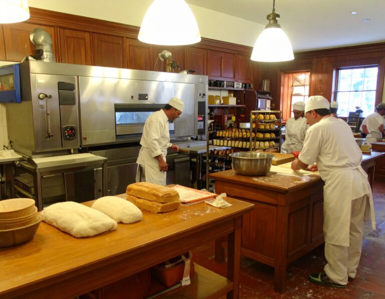 People working in a bakery, with bakery machine in the background - International Bakery